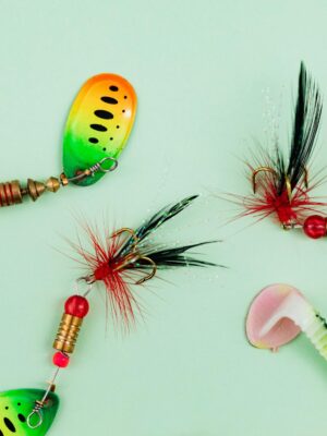 Close-up of vibrant fishing lures and hooks on a green backdrop.