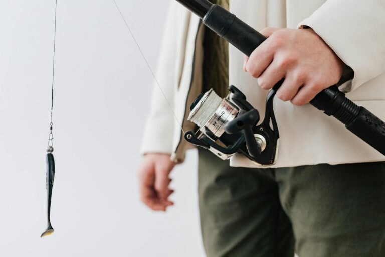 Detailed shot of a hand holding a fishing rod with a lure and reel, perfect for freshwater fishing enthusiasts.